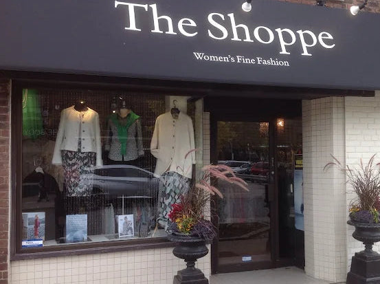 Storefront of 'The Shoppe' with mannequins and clothing displayed in the window.